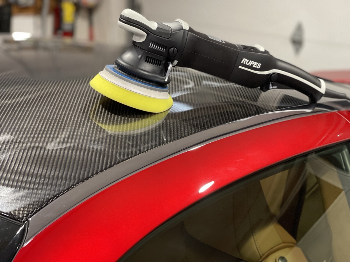 Rupes dual-action polisher with yellow finishing pad polishing red car with carbon fiber roof during multi-stage paint correction at CBA Detailing NJ