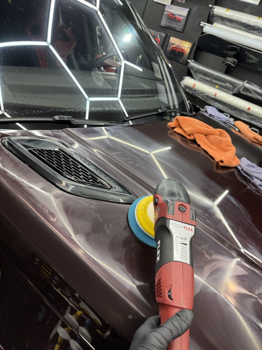 FLEX rotary polisher with blue cutting pad correcting paint on Range Rover fender under hexagonal LED lights at CBA Detailing Bergen County NJ